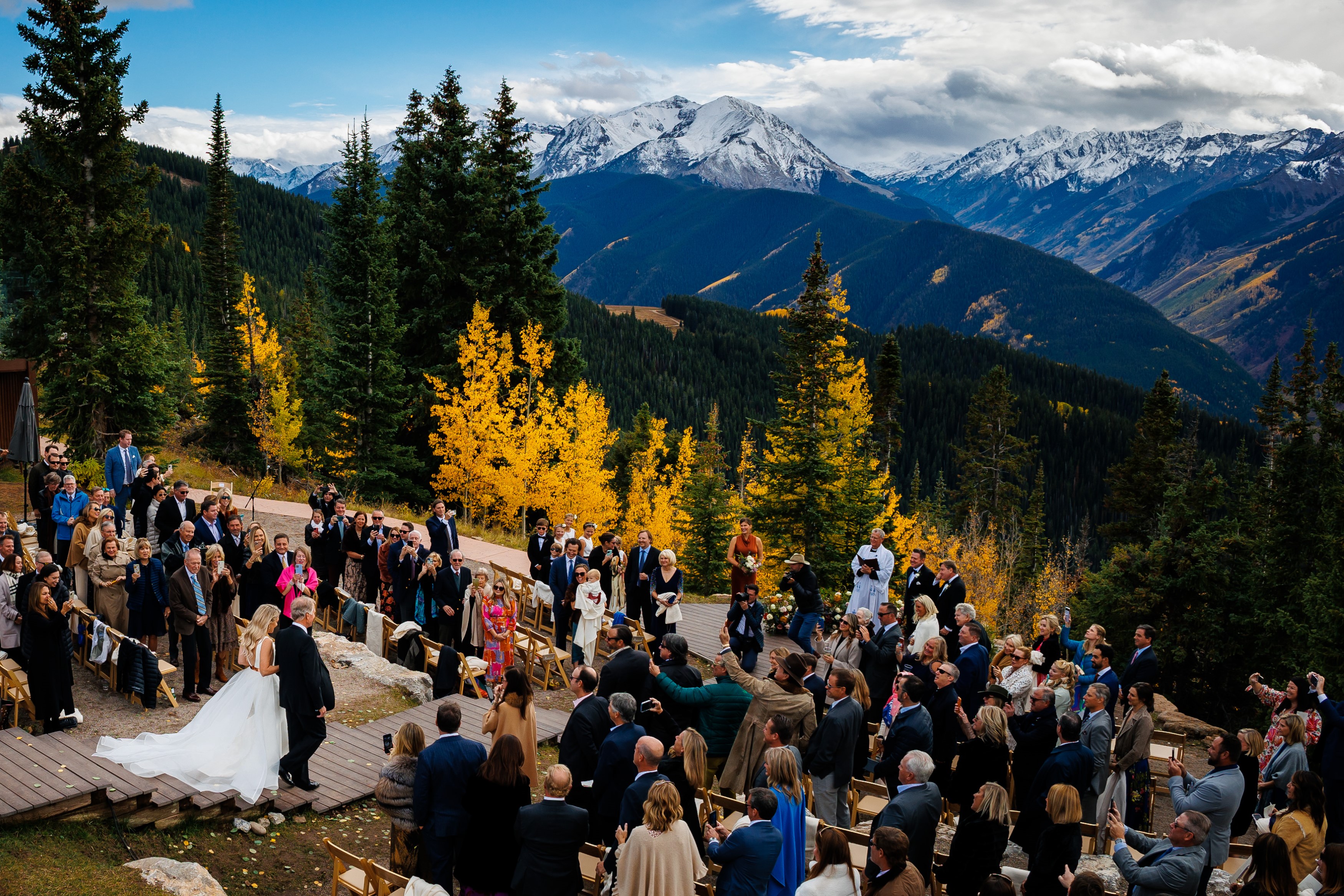 A bride walking down the isle at the Little Nell's Aspen Wedding Deck for a fall wedding ceremony.