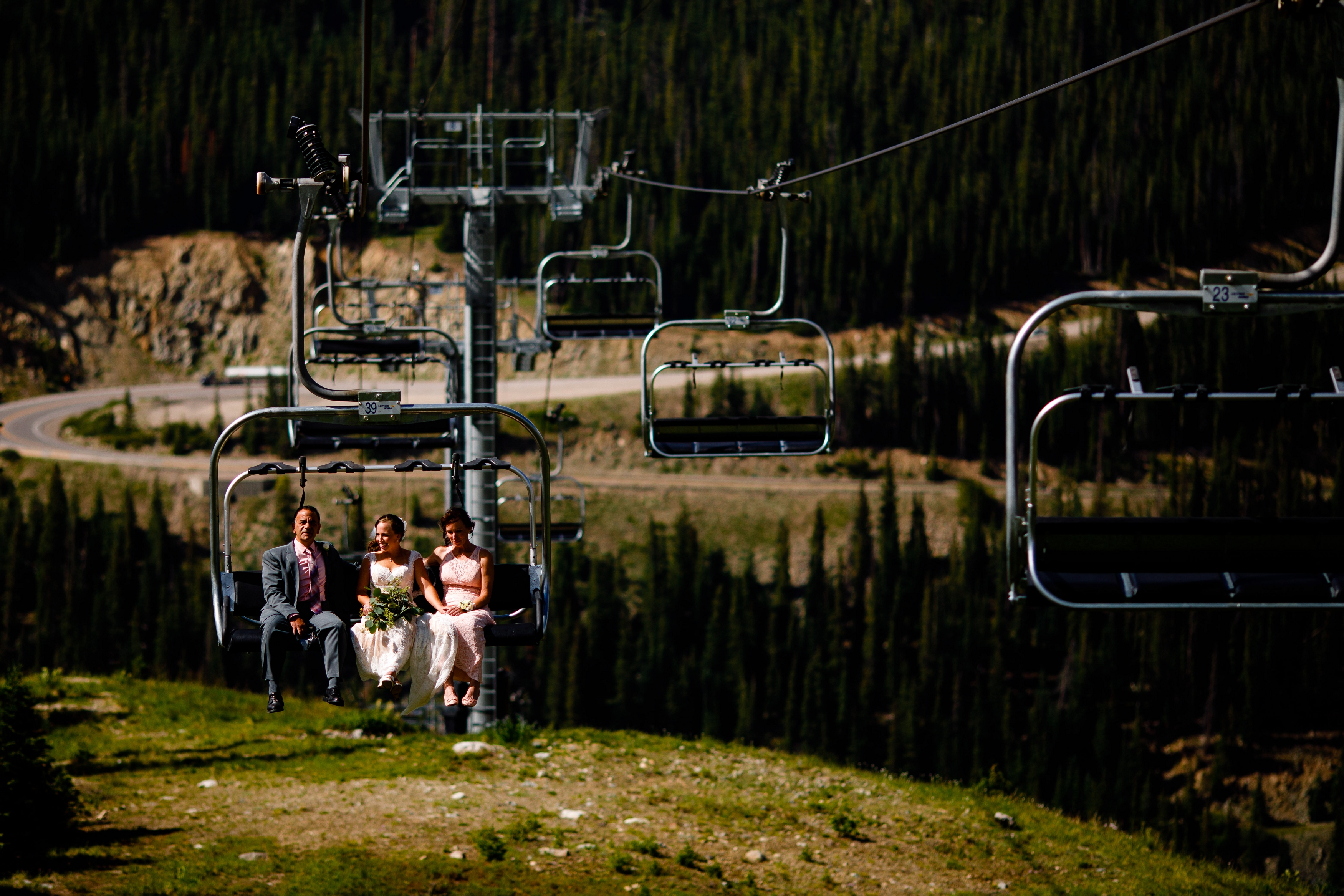 Bride riding the chairlift with her parents before walking down the isle to get married.