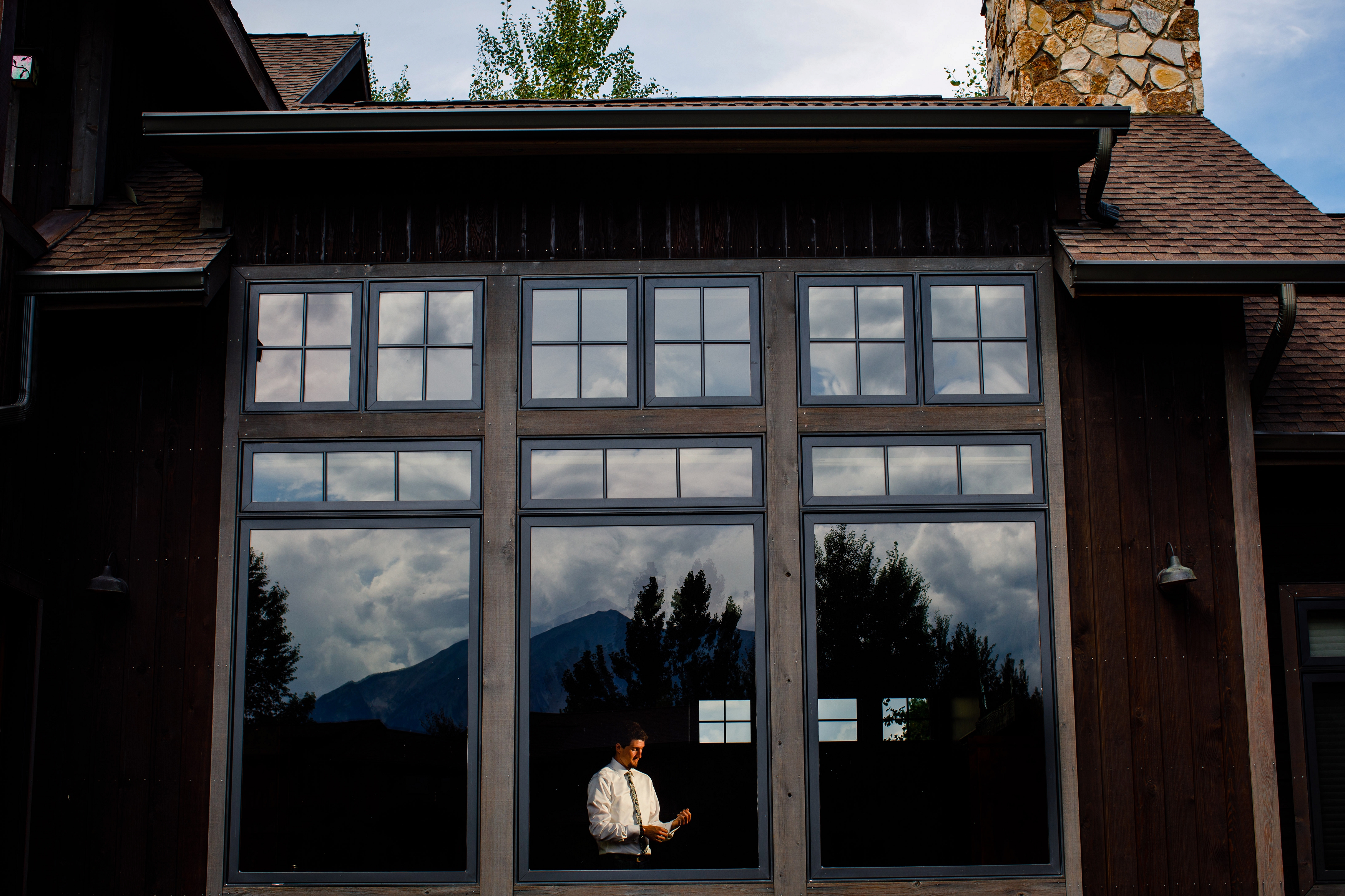 Groom adorns his cufflinks at a mansion in Carbondale with Mt Sopris in the background.