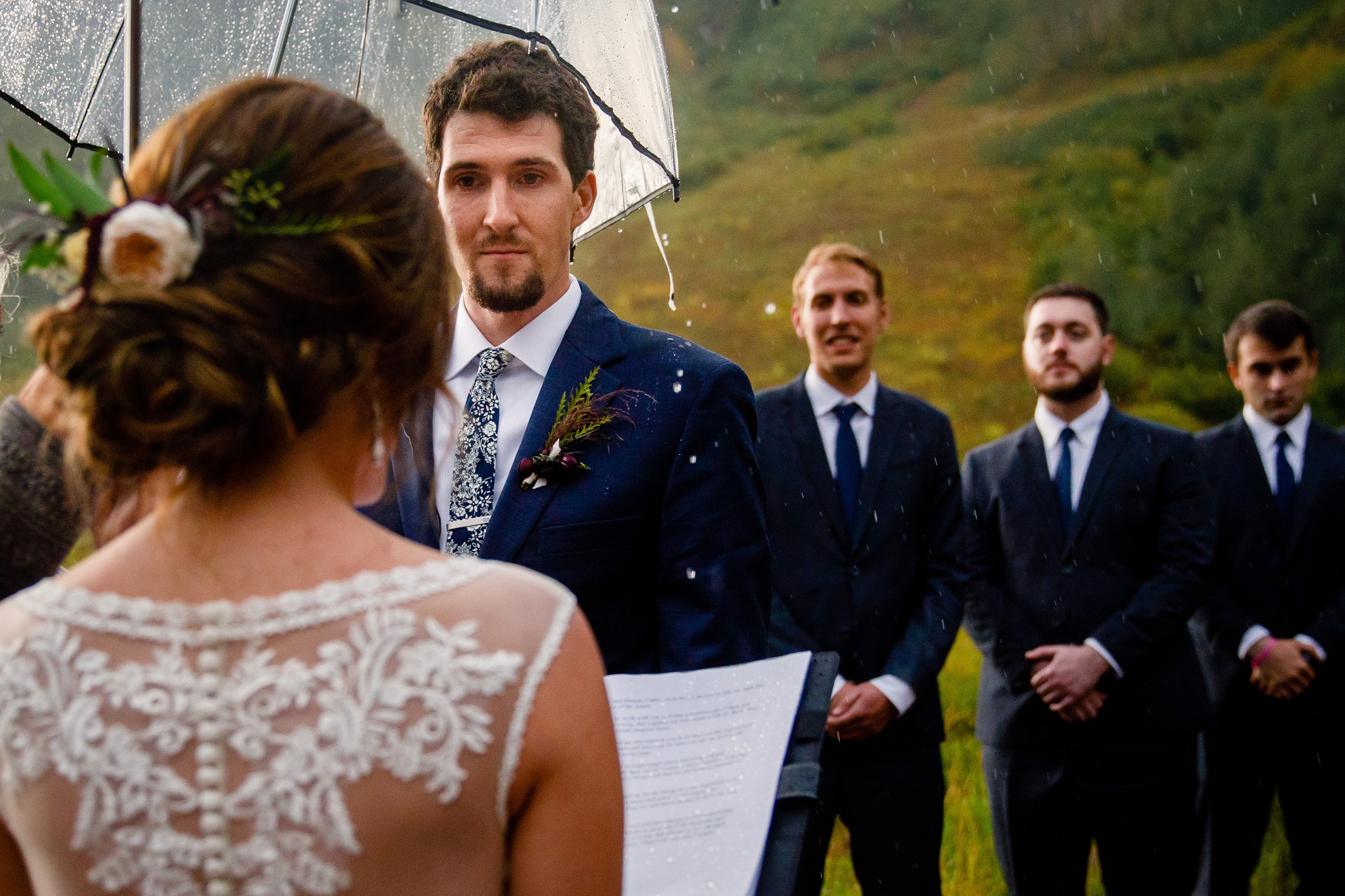 Rain pouring off the umbrella as a bride reads her vows at the Maroon Bells.