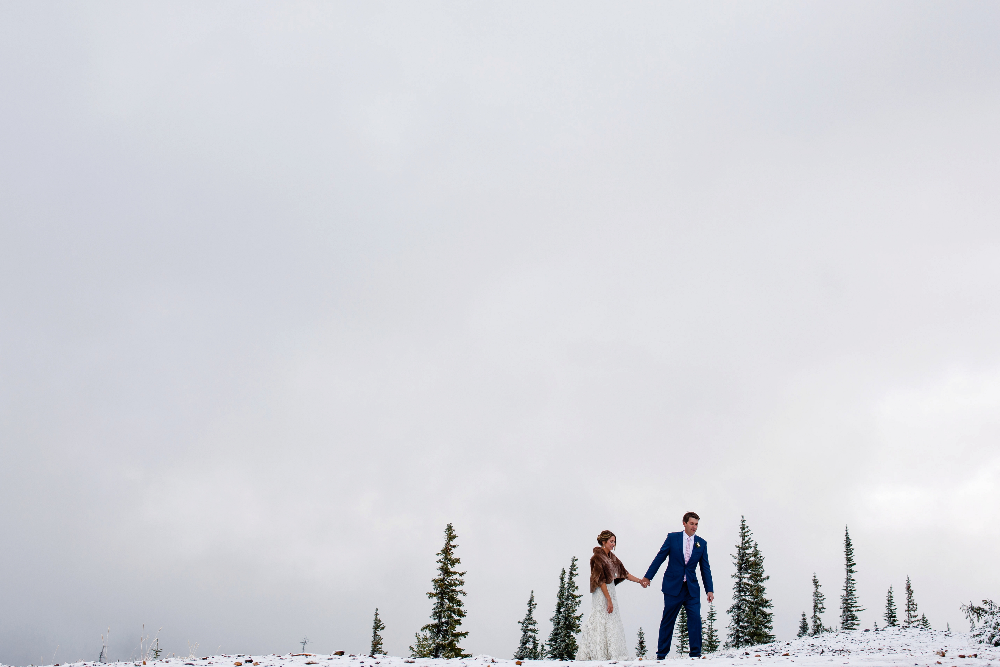 A bride & groom walk in the snow for their portraits during their Tenmile Station Fall Wedding.