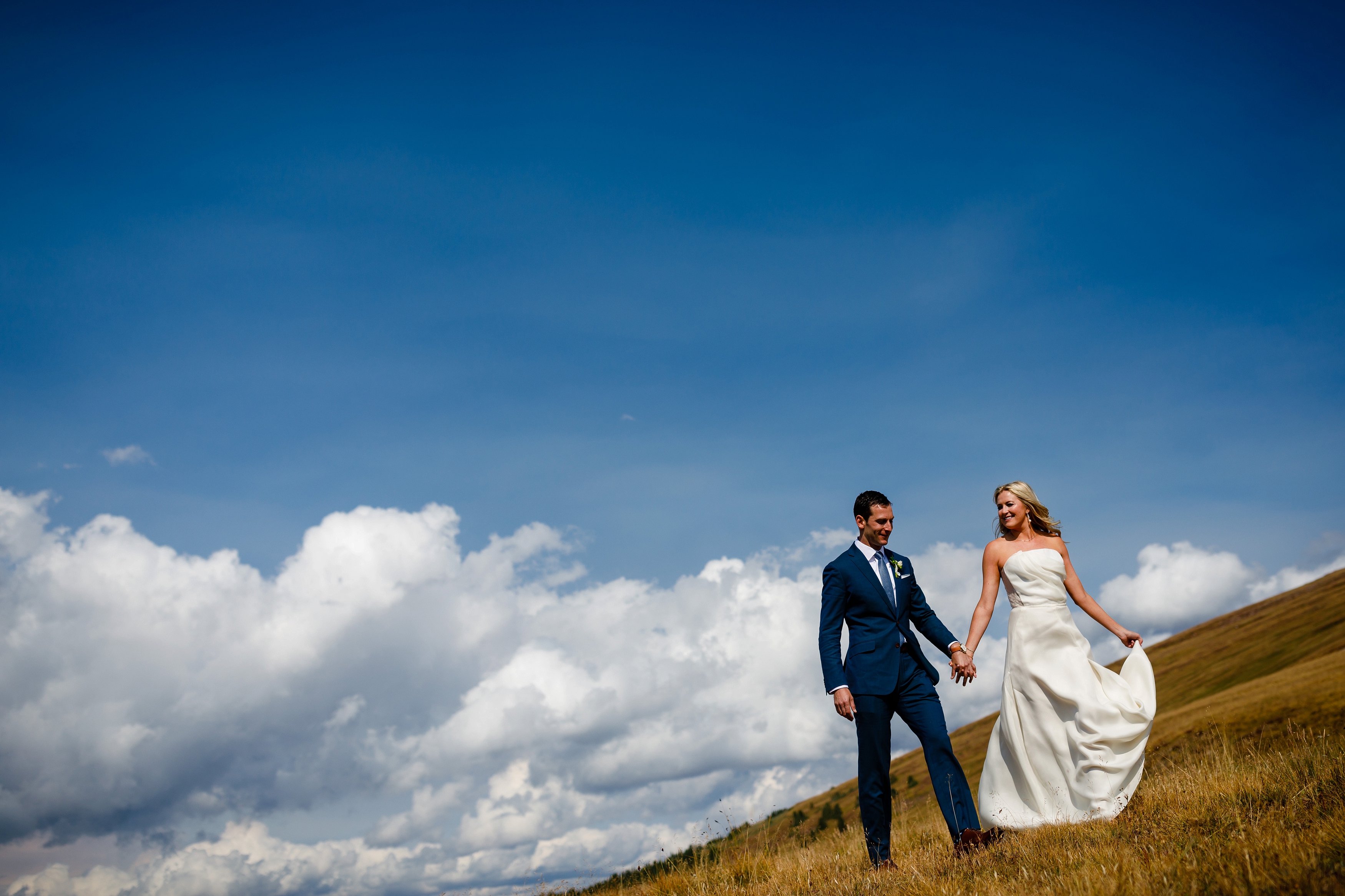 The bride & groom walk hand-in-hand on top of Ptarmigan Pass just before their ceremony at Camp Hale.