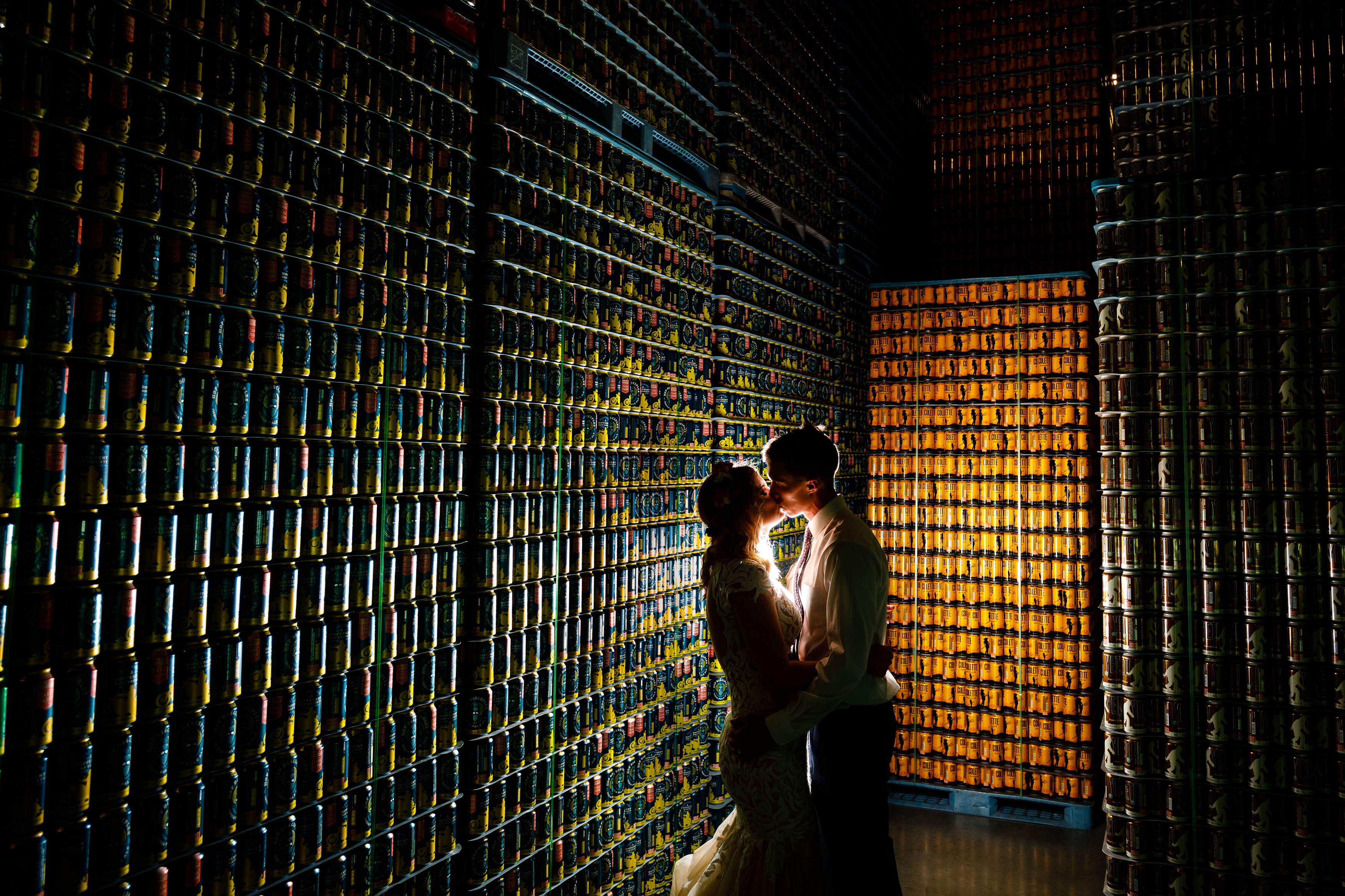 A nightcap portrait of Jake & Jessica in front of thousands of Great Divide beer cans during their wedding reception at Great Divide Brewery.