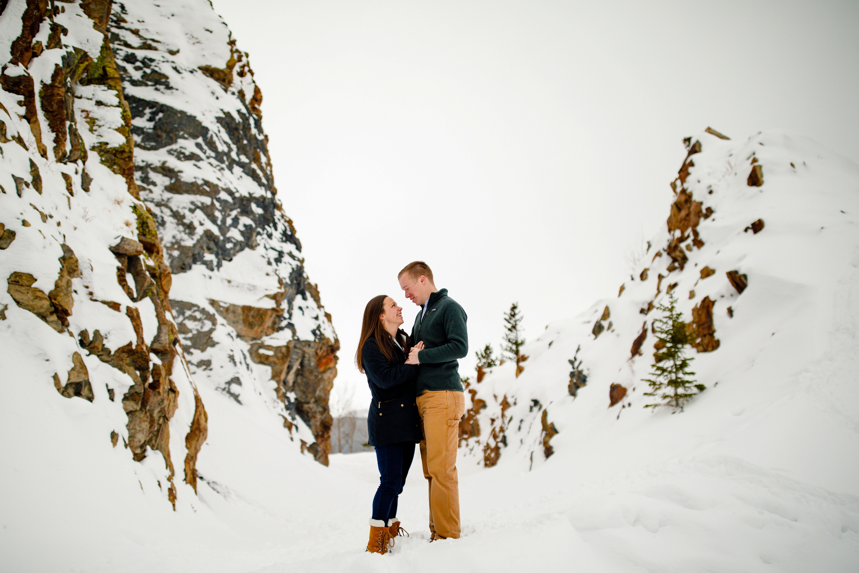 Brendan & Marisa stand between two rock outcroppings for their Snow Engagement in Breckenridge.